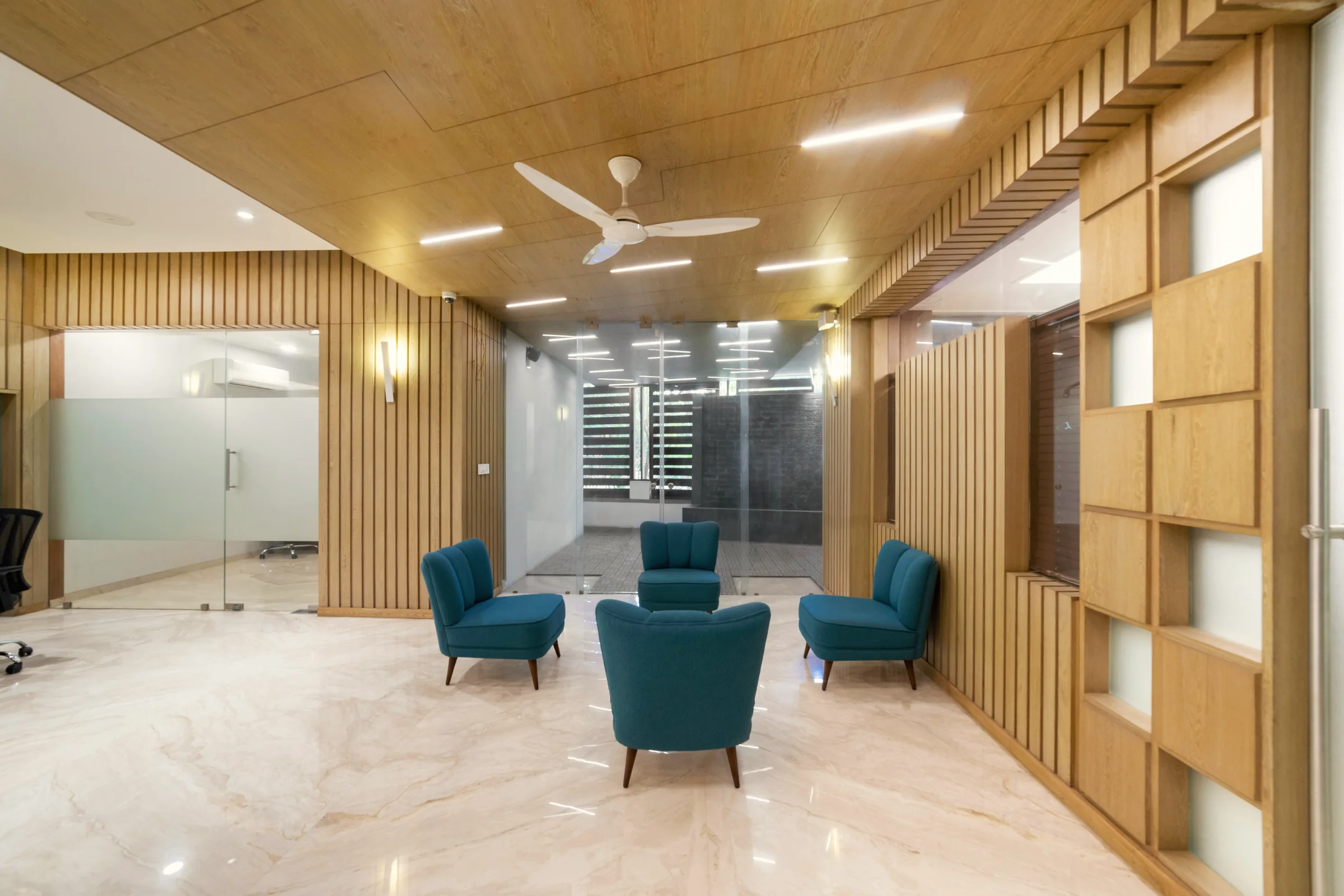 A finished office reception with timber-slatted walls and teal lounge chairs